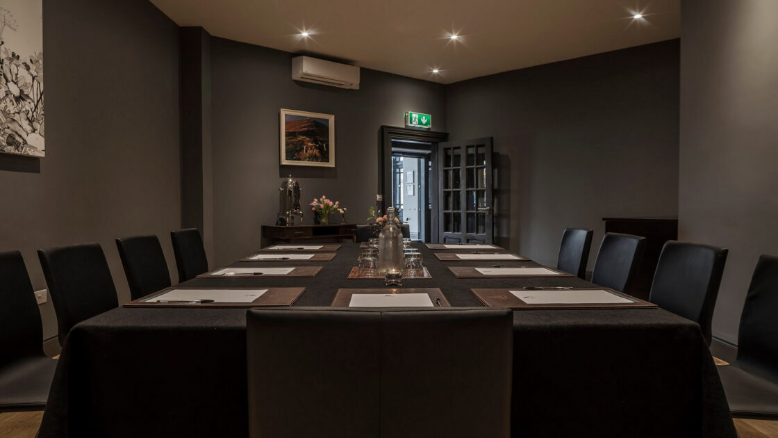 Elegant boardroom with modern decor, conference table set for meeting, ambient lighting, ideal for business events.
