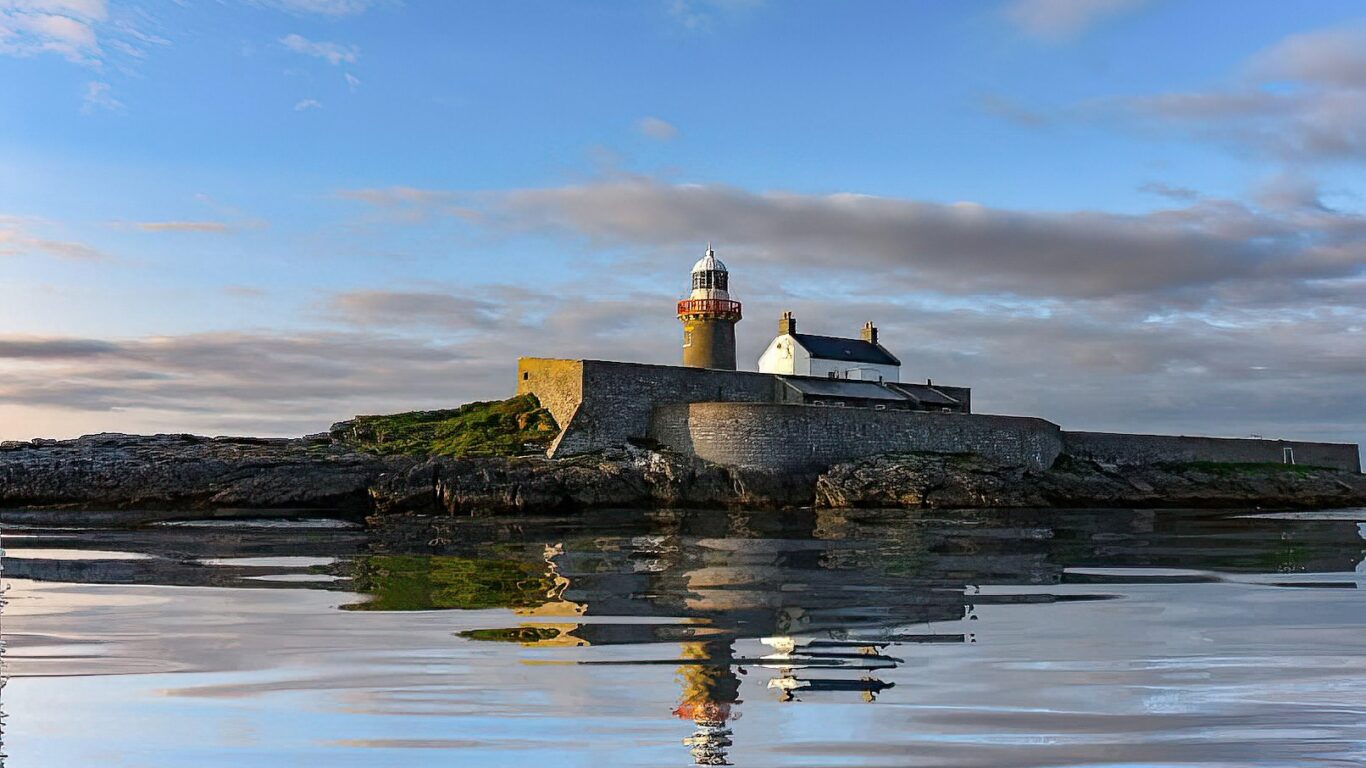 Majestic coastal sunset view of a historic lighthouse on rugged cliffs, ideal for a serene seaside getaway.