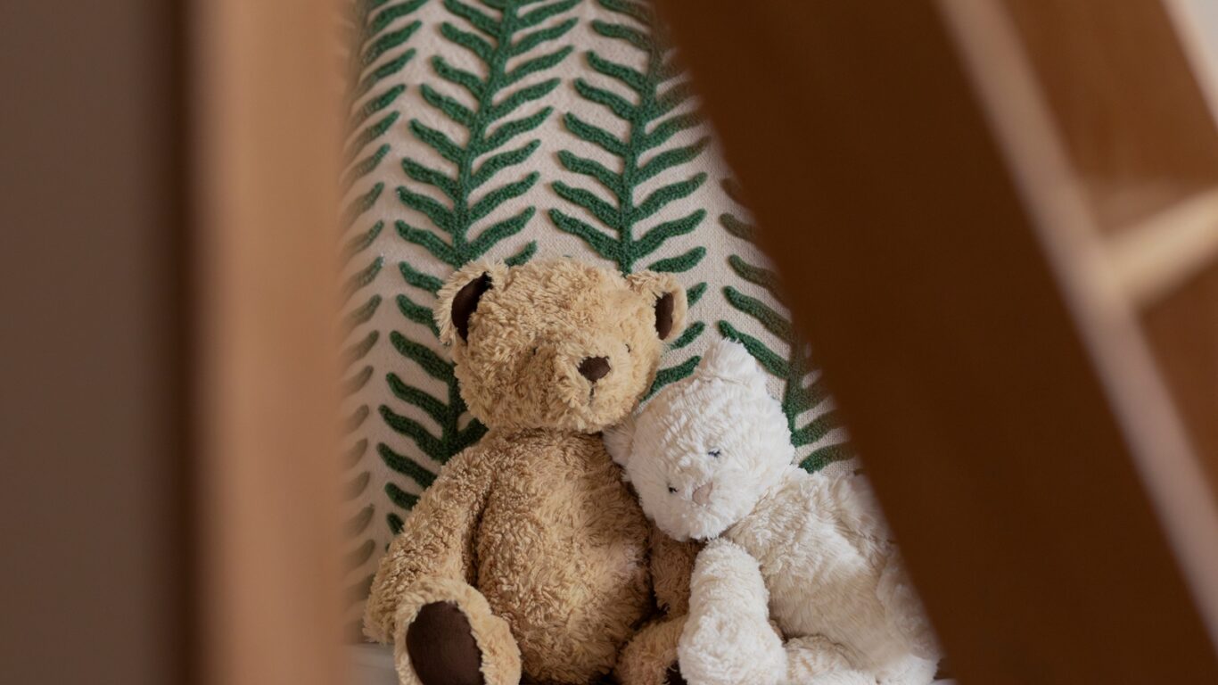 Cosy children's room with cuddly teddy bears on a bed and a leafy cushion, perfect for a family-friendly stay.
