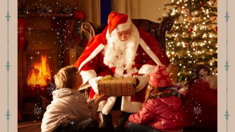 Santa Claus with two children by a cosy fireplace and lit Christmas tree, exchanging gifts in a festive hotel setting.